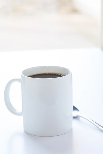 Witte mok van koffie op witte teller in venster — Stockfoto