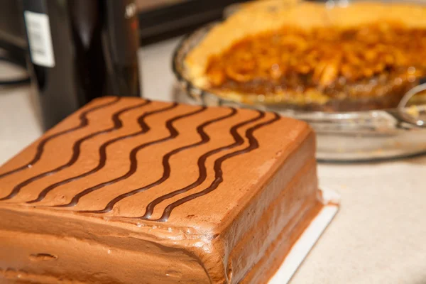 美国山核桃馅饼和葡萄酒瓶在背景中的巧克力蛋糕 — 图库照片