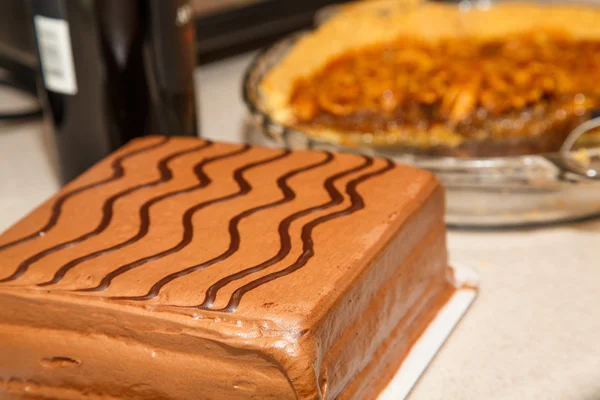 Bolo de chocolate com torta de Pecan e garrafa de vinho no fundo — Fotografia de Stock