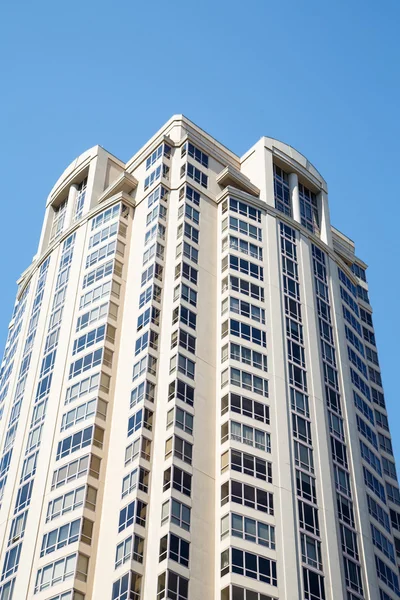 Torre de condominio blanco bajo cielos azules — Foto de Stock