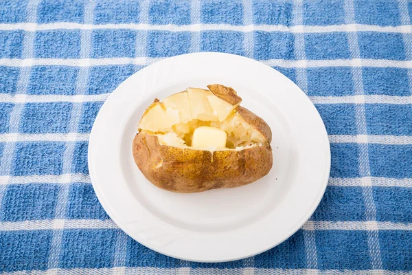 Gebutterte Ofenkartoffeln auf blau kariertem Tischset — Stockfoto