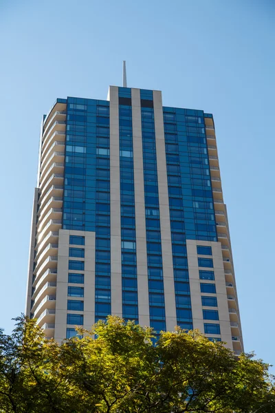 Pedra marrom e torre de vidro azul sob céus azuis — Fotografia de Stock