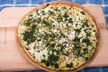 ahşap tahta üzerinde beyaz ve ıspanaklı peynirli pizza