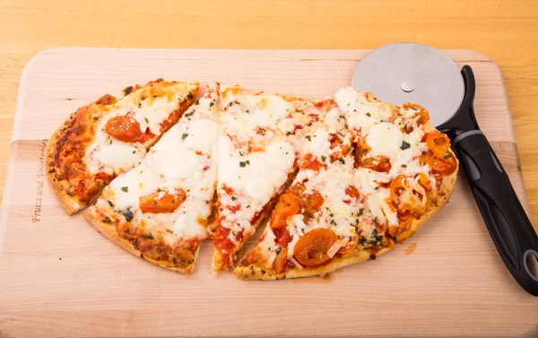 Ovale Pizza in Scheiben geschnitten auf Holzbrett — Stockfoto