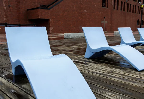 Blauwe chaise lounges op houten pier door bakstenen gebouw — Stockfoto