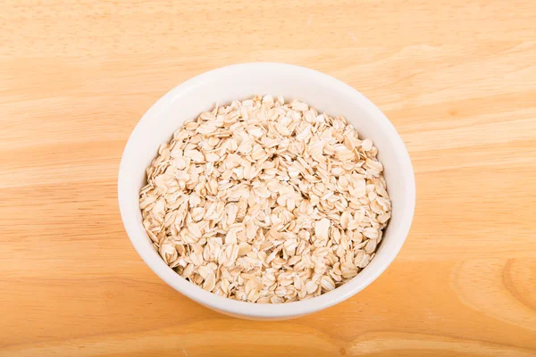 Dry Oats in White Bowl on Wood Table — Stock Photo, Image