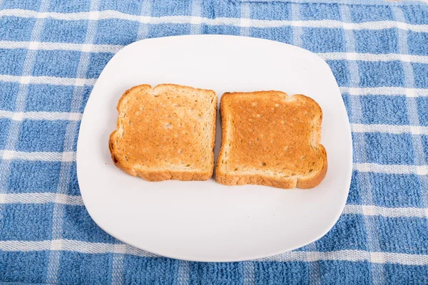 Due pezzi di pane tostato su un piatto bianco . — Foto Stock