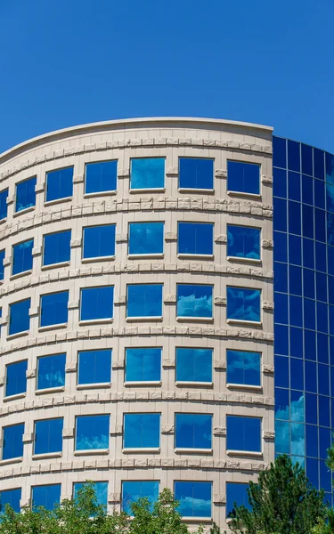 Escritório curvo com nuvens refletidas em vidro azul — Fotografia de Stock