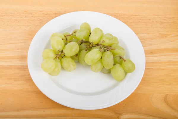 Vita druvor på vit tallrik och bord av trä — Stockfoto