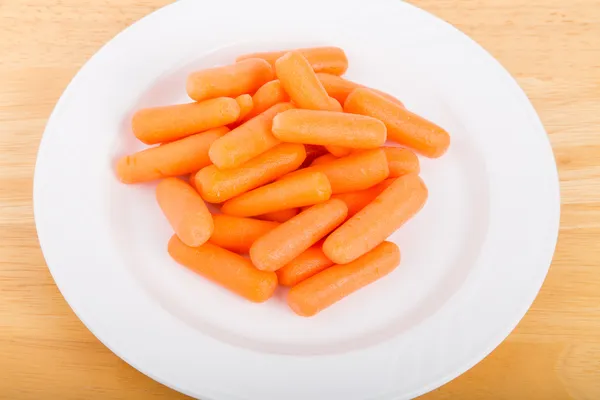 Детская морковка на белой тарелке — стоковое фото