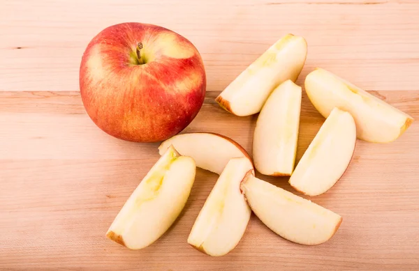 Ganze und geschnittene Äpfel auf Holzschneidebrett — Stockfoto