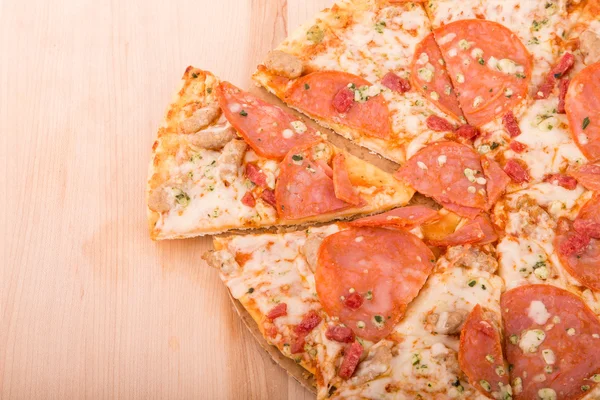 Pizza de pepperoni fatiado na placa de corte de madeira com espaço de cópia — Fotografia de Stock