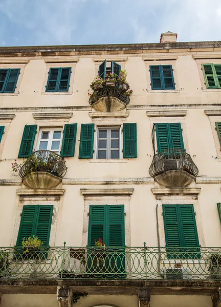 Balcones y maceteros en edificio antiguo con persianas verdes —  Fotos de Stock