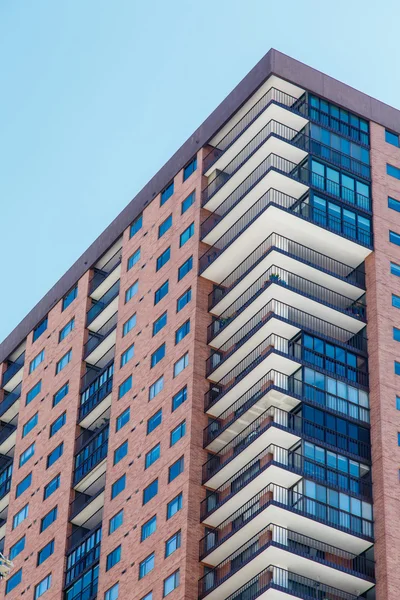 Wohnungen aus rotem Backstein mit weißen Balkonen und blauen Fenstern — Stockfoto
