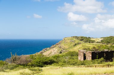 mavi deniz üzerinde yeşil tepedeki eski bina
