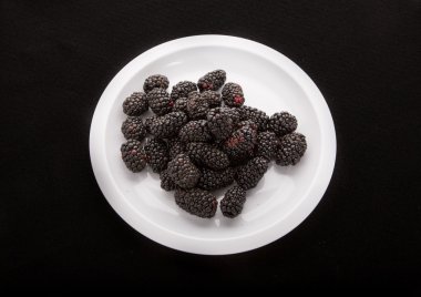 siyah zemin üzerine beyaz tabakta böğürtlen