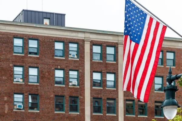 Amerikanska flaggan med gamla tegelbyggnaden i bakgrunden — Stockfoto