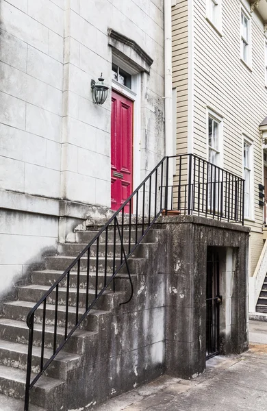 Красная дверь в старом доме вверх по бетонным ступенькам — стоковое фото