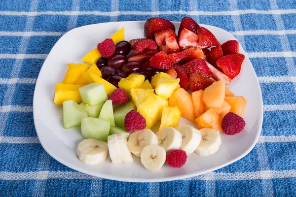 Tropische Früchte auf weißem Teller und blauem Handtuch schneiden — Stockfoto