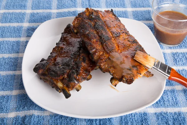 Borstelen saus op barbecue ribs — Stockfoto