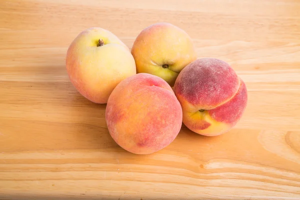 Fyra färska persikor på ett bord av trä — Stockfoto