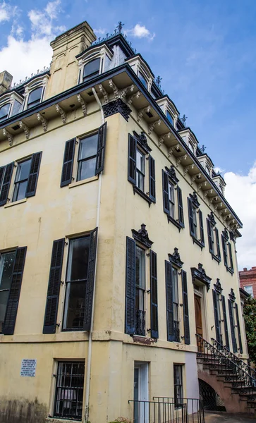 Oud gebouw met zwarte shutters en smeedijzeren trim — Stockfoto