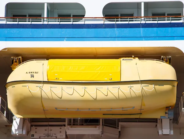 Barco salvavidas amarillo bajo mamparo azul — Foto de Stock