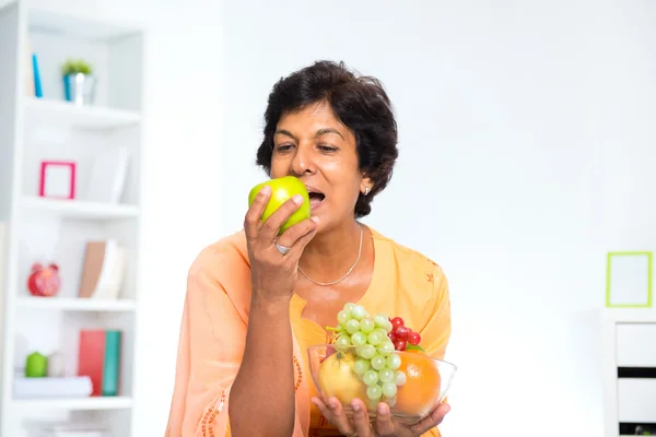 Mature Indian woman eating fruits — Stock Photo, Image