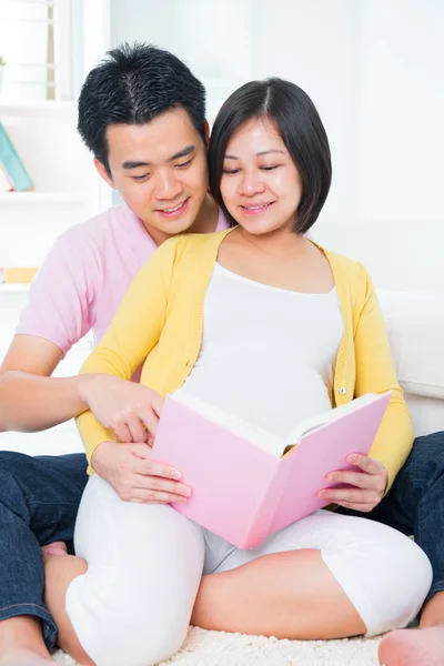 Asian pregnant couple reading book — Stock Photo, Image