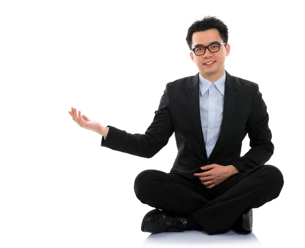 Asiático hombre de negocios mostrando espacio en blanco sentarse en piso — Foto de Stock