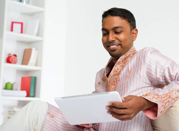 Homem indiano usando tablet digital em casa . — Fotografia de Stock
