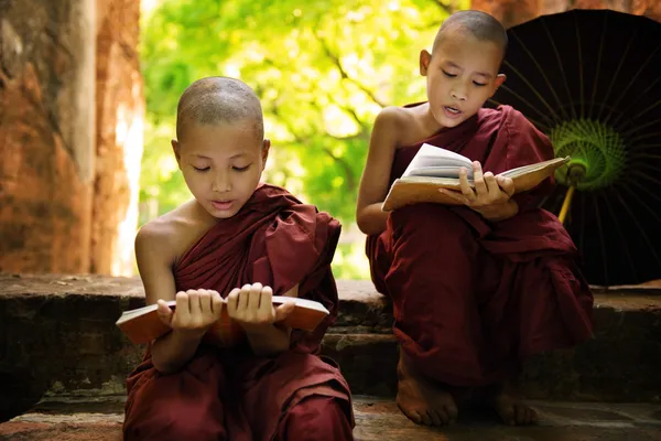 Myanmar pequeno monge leitura livro fora mosteiro — Fotografia de Stock