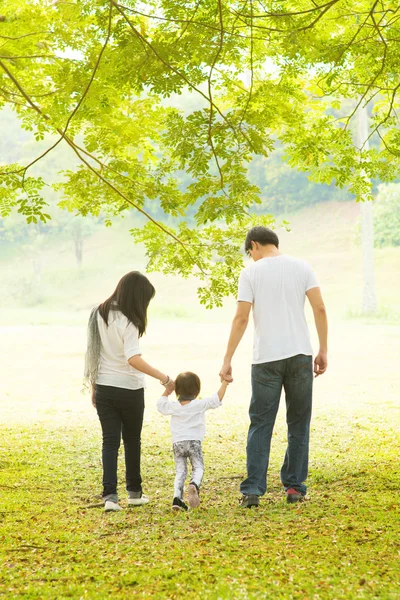 Los padres y la hija se divierten y caminan sobre césped verde . — Foto de Stock