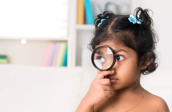 Schattig Indiase meisje gluren door vergrootglas. — Stockfoto