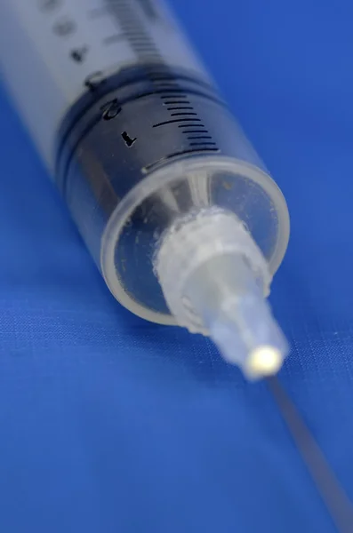 Syringe on a blue background concept of medical treatment — Stock Photo, Image