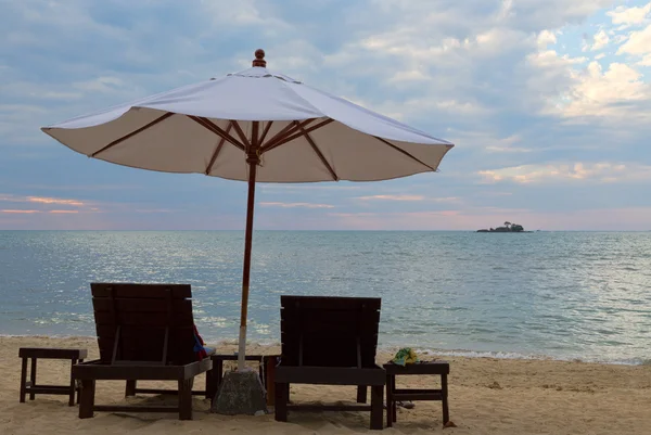 Dwa łóżka i parasol na plaży o zachodzie słońca — Zdjęcie stockowe