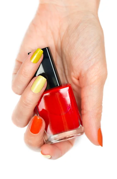 Een fles rode nagellak in een vrouwelijke hand — Stockfoto