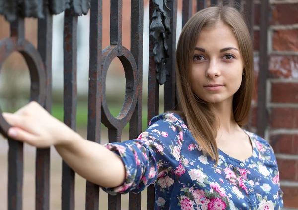 Porträt eines schönen Mädchens am alten rostigen Schmiedezaun — Stockfoto