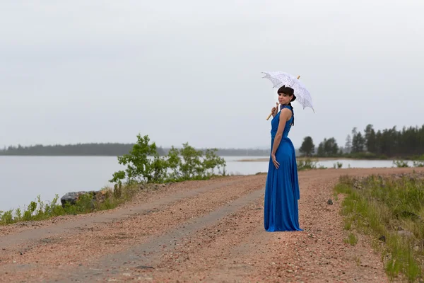 Belle fille dans une robe bleue avec un parapluie — Photo