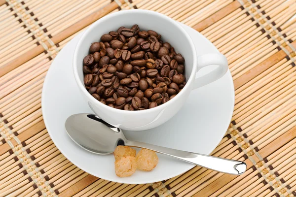 Cup with a spoon and sugar with coffee beans — Stock Photo, Image