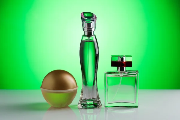 Trzy butelki perfum na jasnym zielonym tle — Zdjęcie stockowe