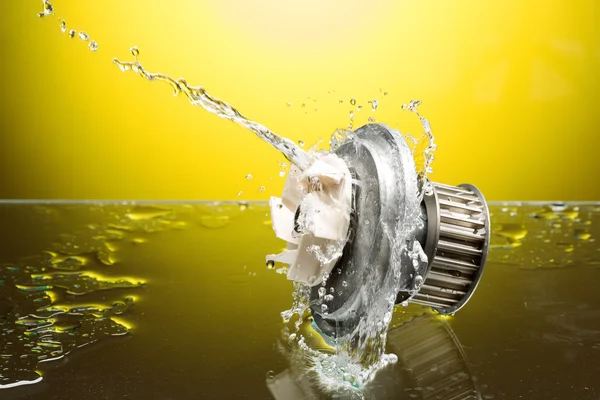 Auto parts, engine cooling pump in water splash on yellow backgr — Stock Photo, Image