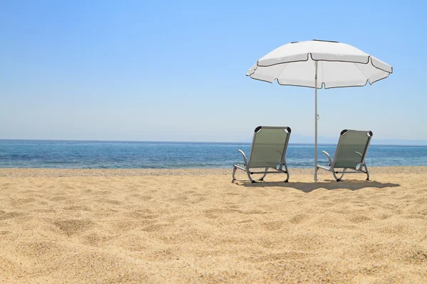 Зонтик и шезлонги на идиллическом пляже — стоковое фото