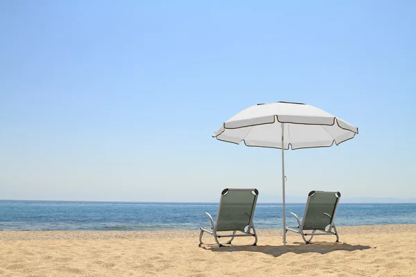 Umbrella and lounge chairs on idyllic beach — Stock Photo, Image