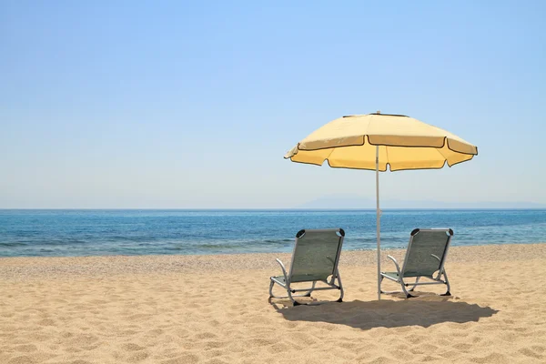 Зонтик и шезлонги на идиллическом пляже — стоковое фото