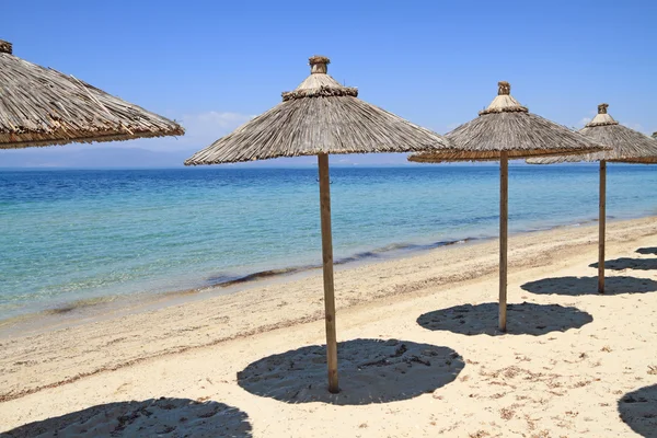 Straw umbrellas by the sea — Stock Photo, Image