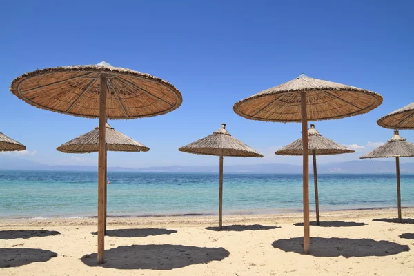 Straw umbrellas by the sea — Stock Photo, Image