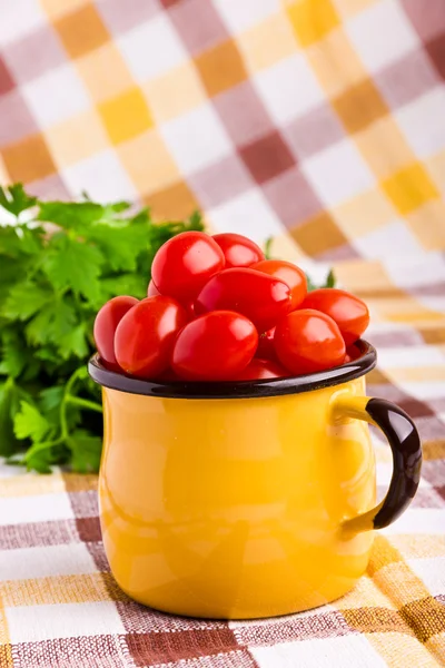 Taza amarilla llena de tomates cherry frescos —  Fotos de Stock
