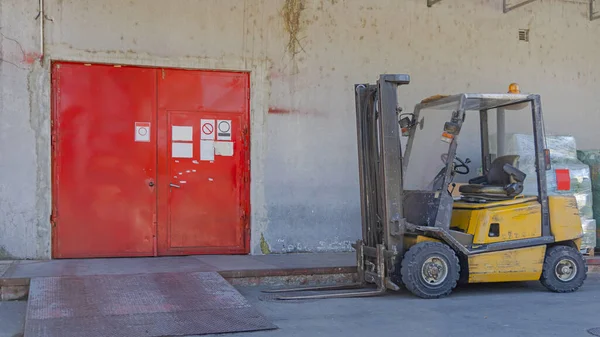 赤いドアの倉庫の前のフォークリフトトラック — ストック写真