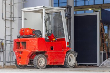 Salondaki küçük kırmızı gaz motorlu forklift.